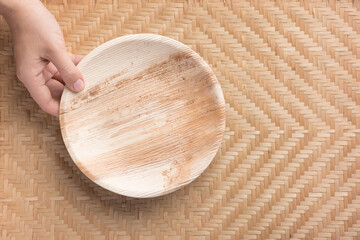 Hand holding Betel palm leaf plate (Biodegradable, Compostable or Eco friendly disposable plate) on...