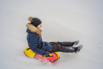 winter, leisure, sport, friendship and people concept - woman sliding down on snow tubes