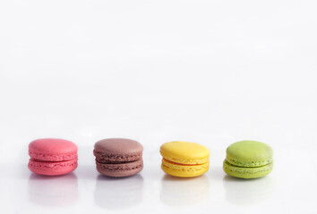 Pink, brown, yellow and green macaron arangment and reflection on white backgrond. Coppy space above.