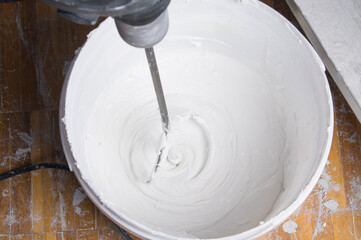 mixing wall putty with a whisk in a bucket, for finishing application