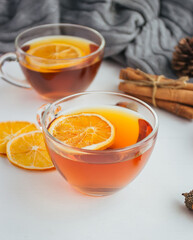 Cup of tea with lemon, cinnamon, pine cones on white table. Cozy autumn lifestyle composition