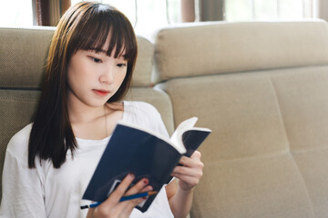 Asian teenager woman reading a book for learn and study at home.