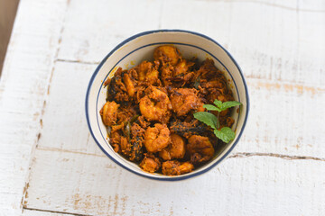 Top view spicy hot Bengali Prawn roast , shrimp masala fish curry. Indian food. Fish fry with red chili, curry leaf. Asian cuisine. Delicious Kerala, Goan fish curry clay pot. Grilled tiger shrimps
