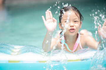 Fototapeta na wymiar .happy little girl playing with inflatable ring in outdoor swimming pool on hot summer day. kids learn to swim. child water toys. children play in tropical resort. family beach vacation.
