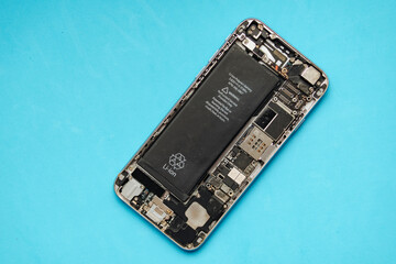 Smartphone motherboard with battery on blue background.