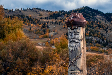 Wooden totem pillar on mountains background in autumn. Orthodox old believers totem. Religious...