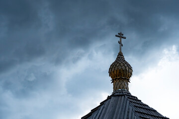 Wooden chapel's dome with orthodox cross on the top with cloudy sky background. Religious symbol. Faith concept.