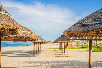 Beach with thatched umbrellas and wooden loungers