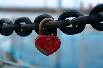 Red padlock on the pier fence chain. Valentine's day.