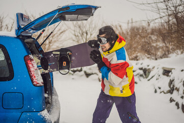 The snowboard does not fit into the car. A snowboarder is trying to stick a snowboard into a car....