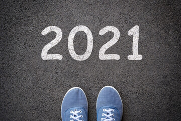 Dlue jeans casual shoes standing on the asphalt concrete road and white sign to new year 2021.