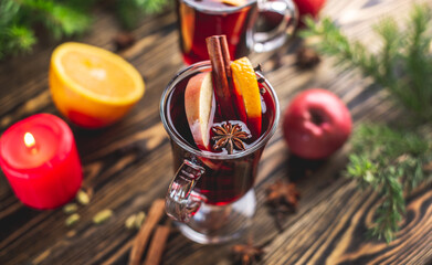 Couple glass cups with mulled wine decorated with cinnamon, star anise and fruit on a wooden table. Concept of a traditional hot winter beverage