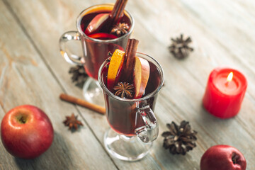 Couple glass cups with mulled wine decorated with cinnamon, star anise and fruit on a wooden table. Concept of a traditional hot winter beverage