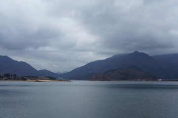 Fototapeta na wymiar 曇り空の河口湖と周辺の山々の風景
