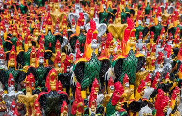 Chicken statues of various colors and sizes that people worship in the mystery of their beliefs.
