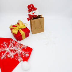 Christmas shopping bag and snowman, red gift box with gold ribbon, Santa hat and snowflakes on white background. Happy new year 2021. Copy space.