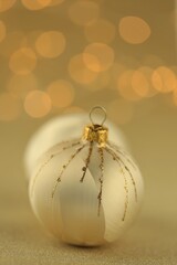 Christmas and New Years festive background.Gold Christmas balls on a light beige background with shining yellow bokeh.winter Holidays Beautiful wallpaper.