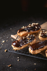 Chocolate eclairs filled with cream on dark background