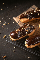 Chocolate eclairs filled with cream on dark background