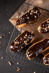 Chocolate eclairs filled with cream on dark background