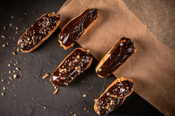 Chocolate eclairs filled with cream on dark background