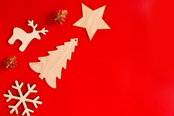 Flat natural unpainted wooden christmas ornaments lie diagonally on red background