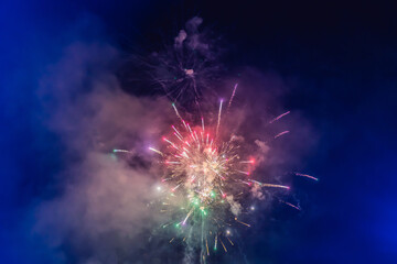 Beautiful colorful holiday fireworks in the evening sky with majestic clouds
