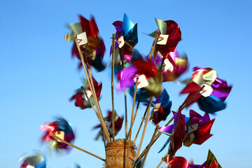 Colorful paper pinwheels spinning with blue sky on background
