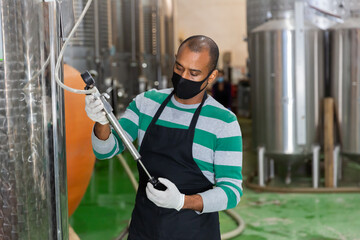 Winery worker checks the pressure in a steel barrel