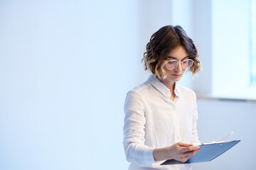 Business woman in the office with documents in the hands of the window in the background finance work