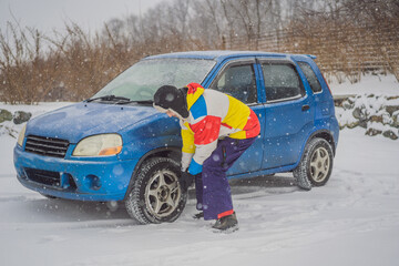 Winter accident on the road. A man changes a wheel during a snowfall. Winter problems