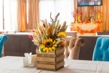 Fall and autumn floral arrangement on table - ideal for Thanksgiving holidays.Autumn bouquet of beautiful flowers, pumpkin in wooden box. festive decoration for Thanksgiving day.