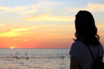 a girl looks at a beautiful sunset on the sea