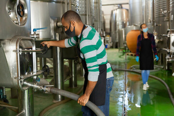 Wine producer controlling production wine in winery, preparing for wine filtration