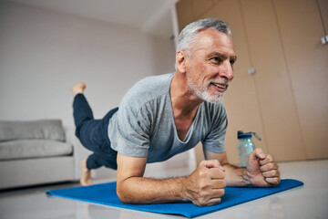 Fit aged man training his muscle endurance in plank position