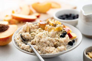 Oatmeal bowl with hemp seeds, peach and raisins. Healthy vegan breakfast food. Oatmeal porridge