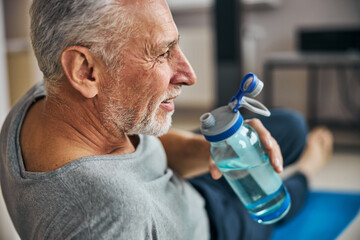 Aged gentleman having a water break during his workout