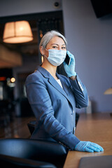 Charming woman in medical mask talking on mobile phone