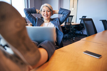 Cheerful businesswoman using modern laptop in office