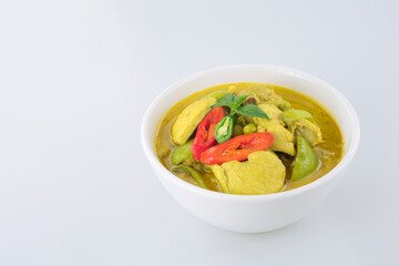 Chicken green curry in white ceramic bowl on white tabletop