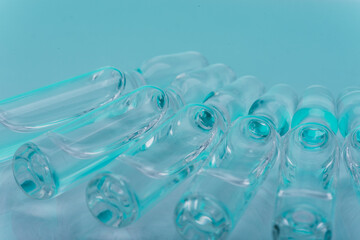 Glass medical ampoule vial for injection. Medicine is liquid sodium chloride with of aqueous solution in ampulla. Close up. Bottles ampule multicolor on background color and water. Human plasma.