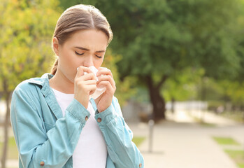 Young woman suffering from allergy outdoors