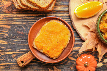 Plate with tasty bread and pumpkin jam on table