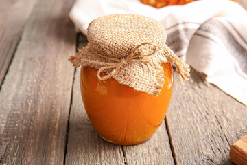 Jar of tasty pumpkin jam on table