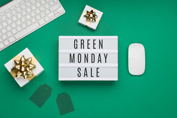 Green Monday sale concept on green paper background with white keyboard, computer mouse, gift boxes and paper tags.