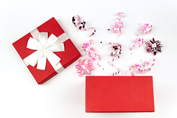 Christmas or New Year composition with red present box and pink gift bows and sparkling shiny decoration on white backcround.