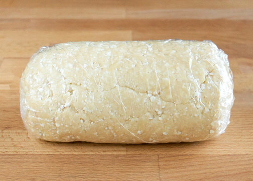 Cottage cheese dough for cookies in cling film on a wooden tabletop