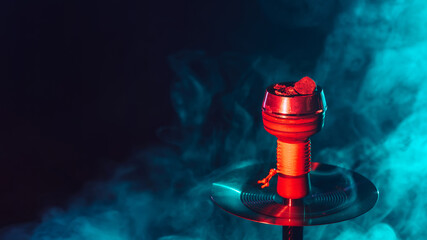 hot red coals for hookah shisha in a metal bowl with smoke on a color background with a copy space