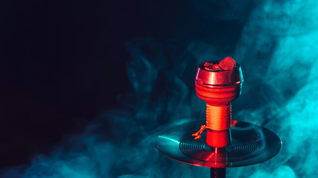 hot red coals for hookah shisha in a metal bowl with smoke on a color background with a copy space