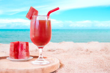 Watermelon juice in glass on wooden plate with blur image of sand beach and blue sea. cocktail drink for summer holidays. Tropical organic fruit. helps to nourish the eyes. 